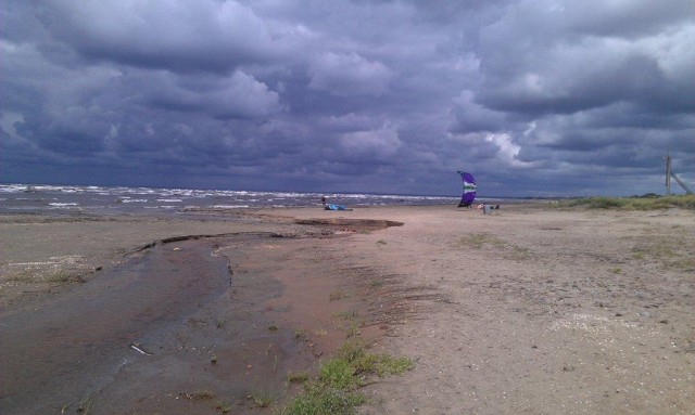 Några kite-surfare var de enda som hade hittat ut i den friska vinden,  åskan lurade vid horisonten